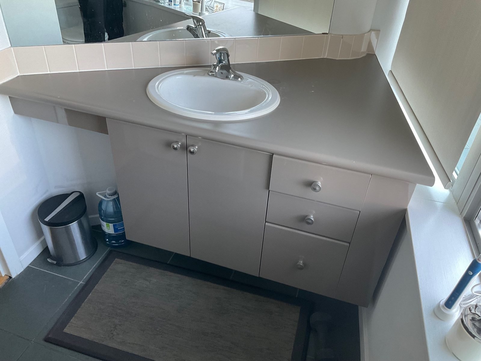 Before: original corner vanity under the window in a West End condo main bathroom