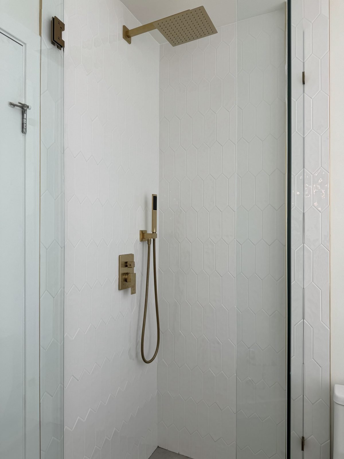 After: main bathroom walk-in shower with a frameless glass door, rain shower and brushed gold fixtures in a West End condo