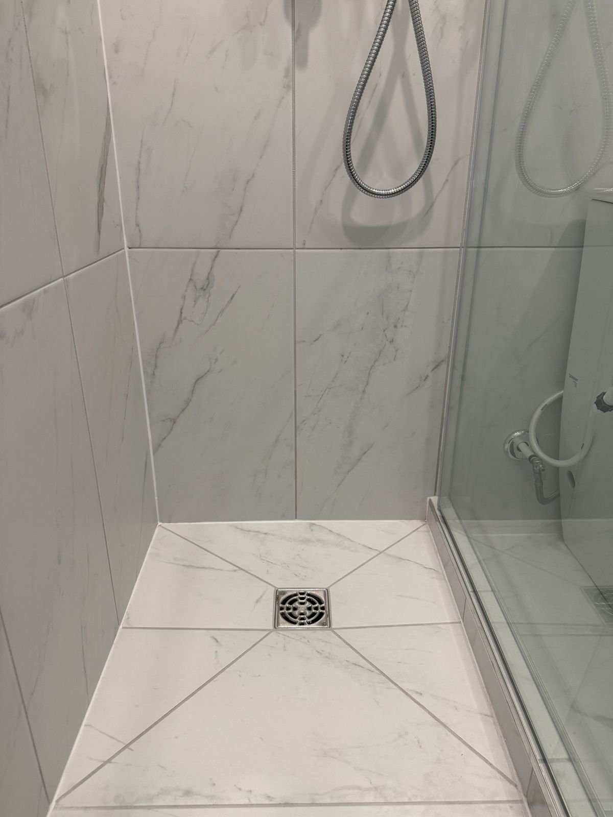 Custom Schluter shower base with marble-look porcelain tile and a square drain in a West Vancouver ensuite