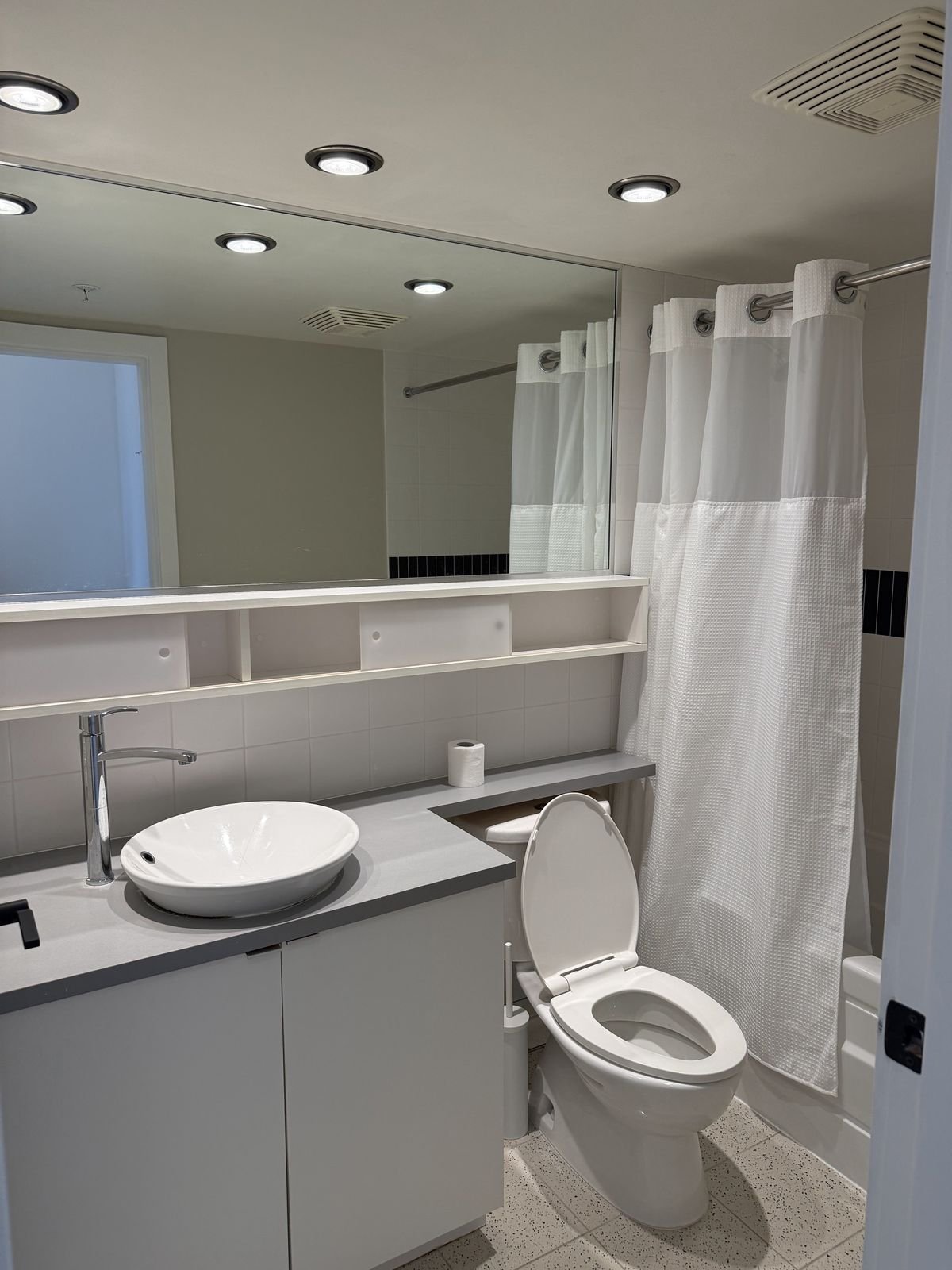 Before: Yaletown condo bathroom with a grey vanity, vessel sink and open shelving