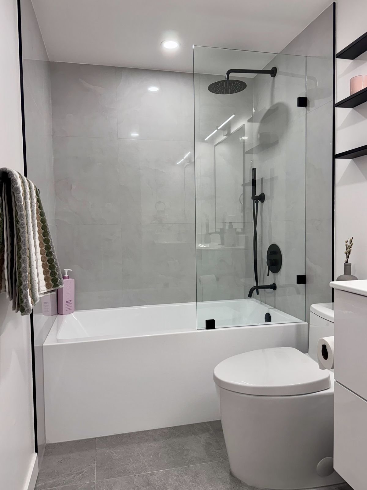 Renovated Yaletown condo bathroom with a new tub, frameless glass screen and matte black fixtures