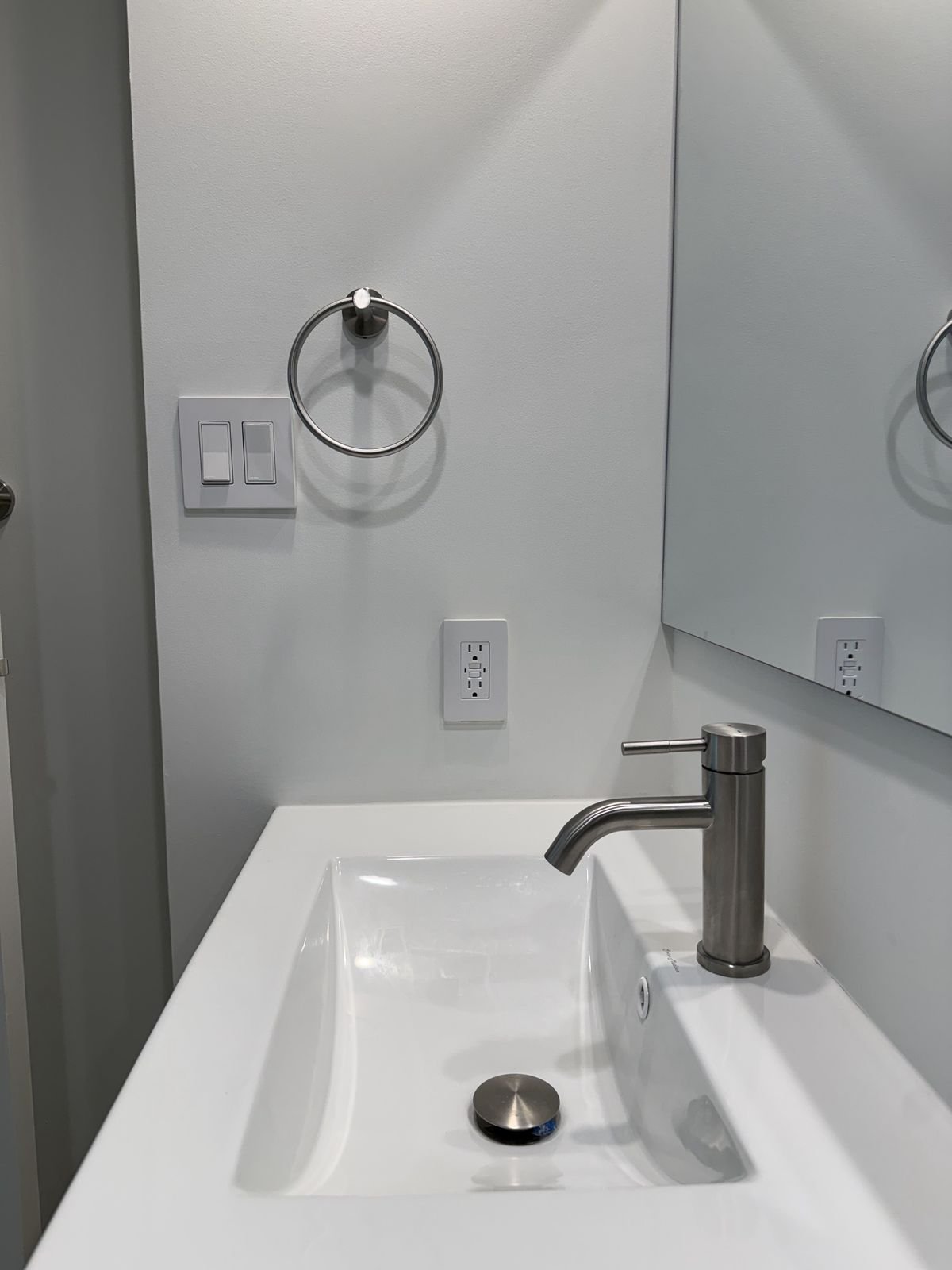 Integrated white vanity sink with a brushed nickel single-hole faucet in a renovated Yaletown condo bathroom