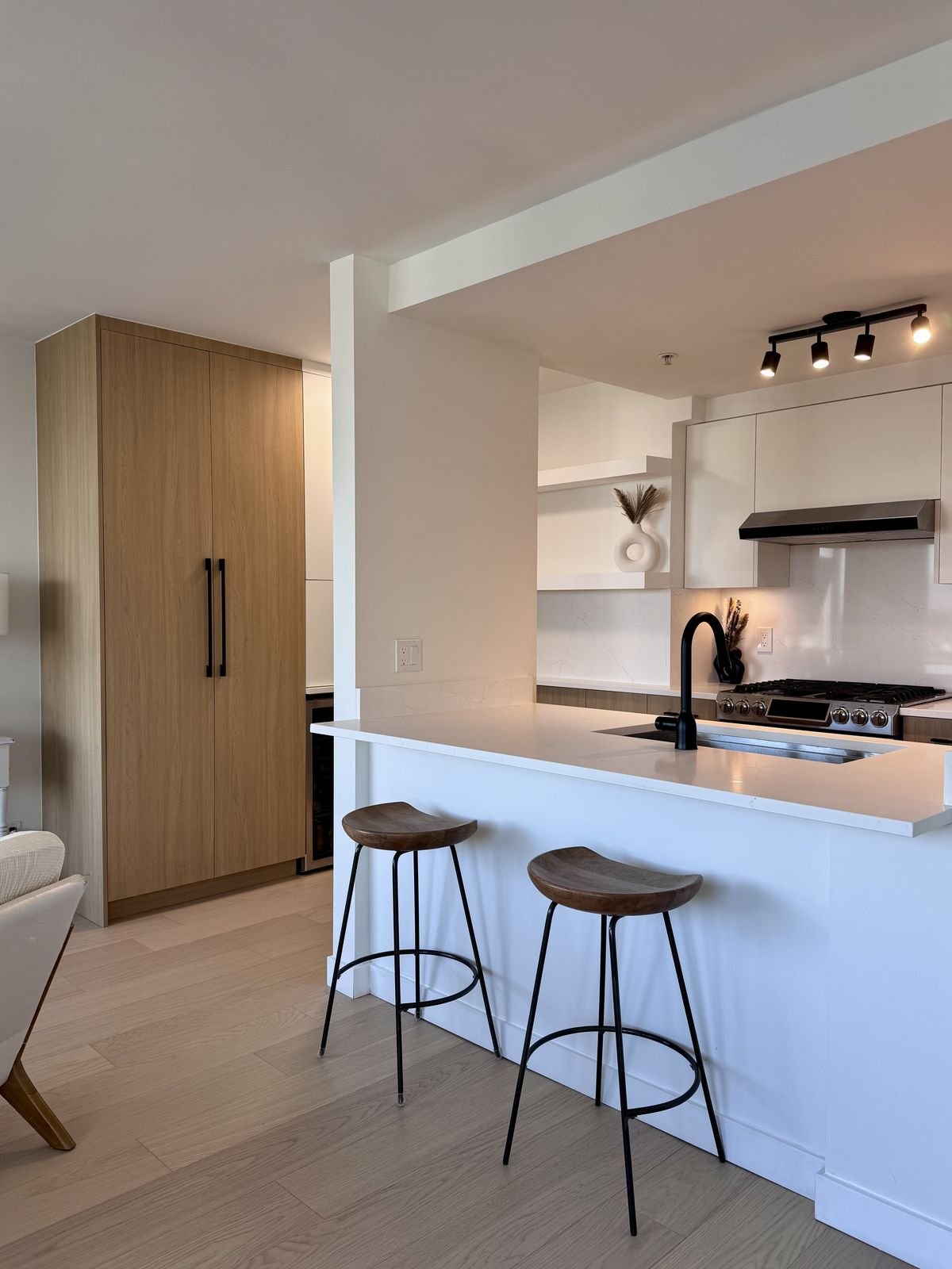 Expanded Yaletown condo kitchen with a quartz peninsula, tall pantry and wood-grain and white cabinets