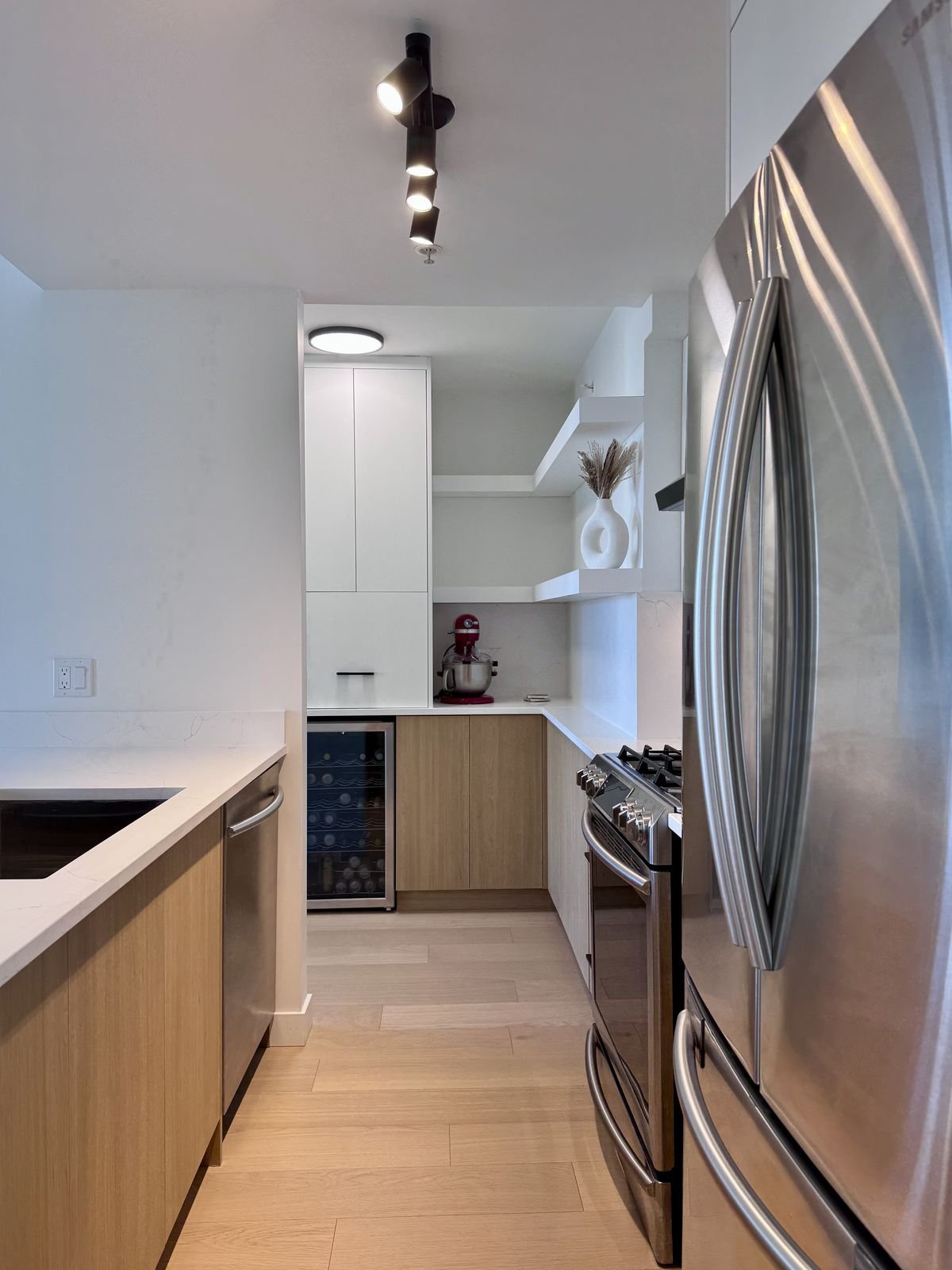 Condo kitchen with a built-in wine fridge, wood-grain cabinets and quartz counters in Yaletown