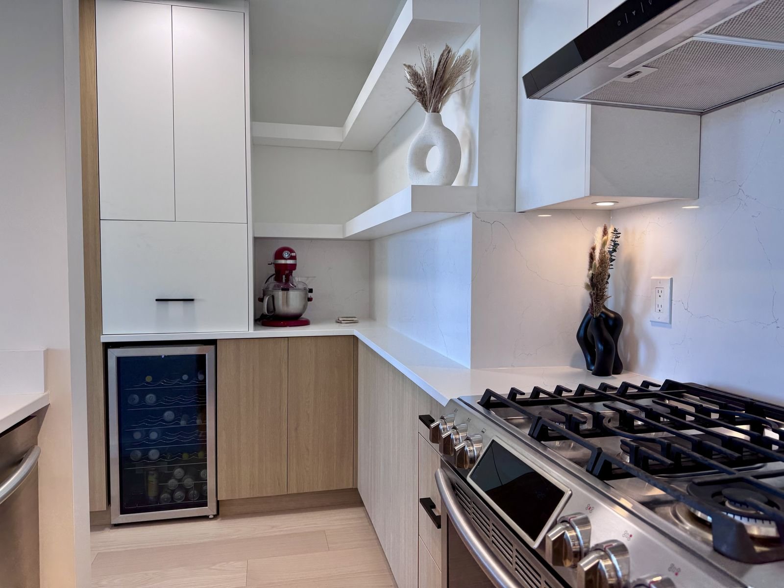 After: range wall with a full-height quartz backsplash, hood fan and wood-grain cabinets in a Yaletown condo