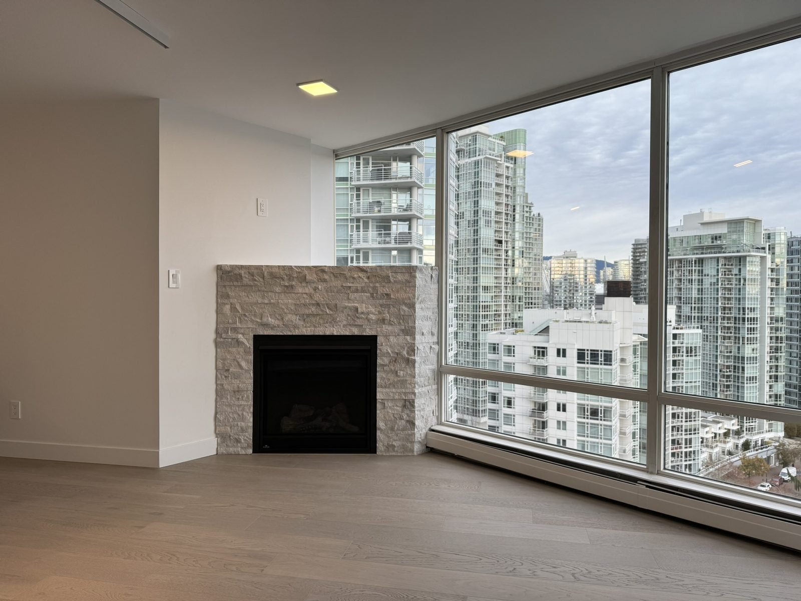New engineered hardwood flooring and smooth ceilings in the living room of a renovated Yaletown condo