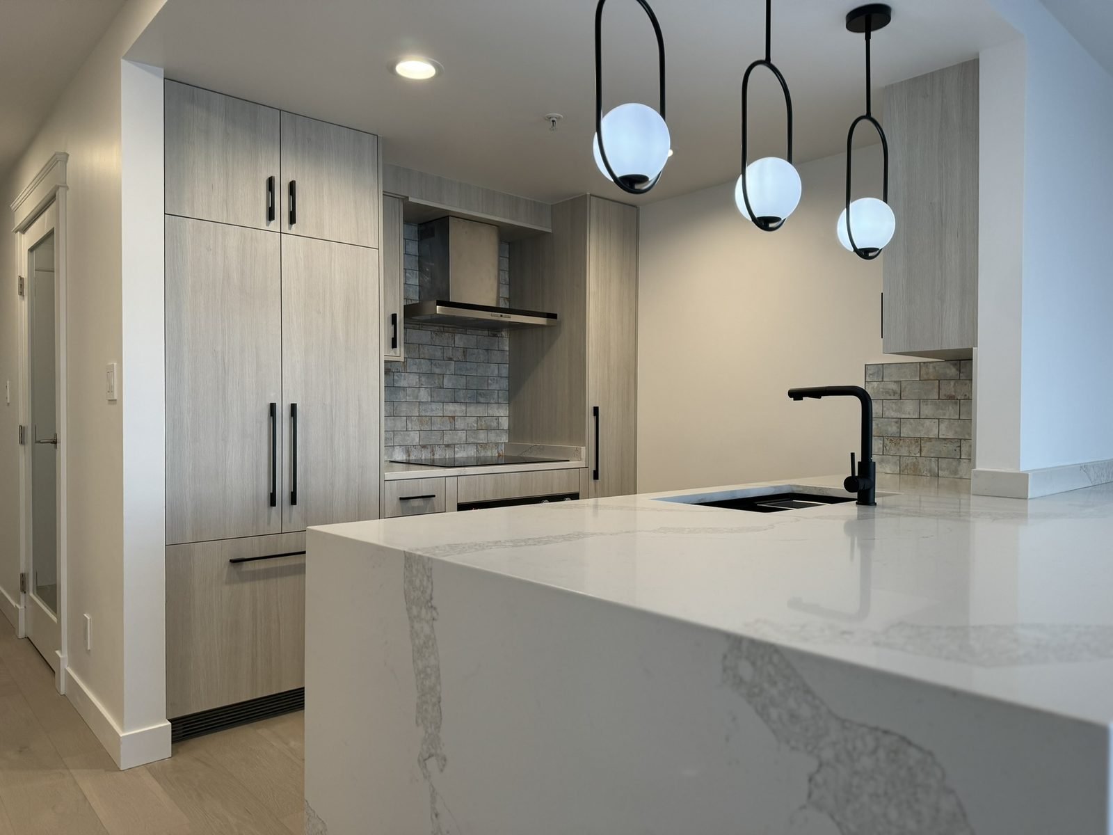 Quartz waterfall island and tall panel-ready fridge wall in a renovated Yaletown, Vancouver kitchen