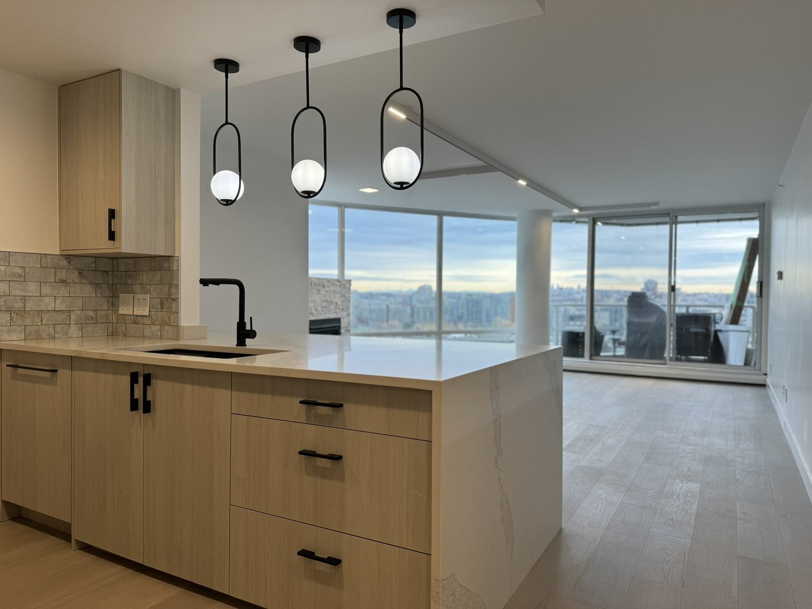 Opened-up Yaletown condo kitchen with wood-grain cabinets, a quartz waterfall island and False Creek views