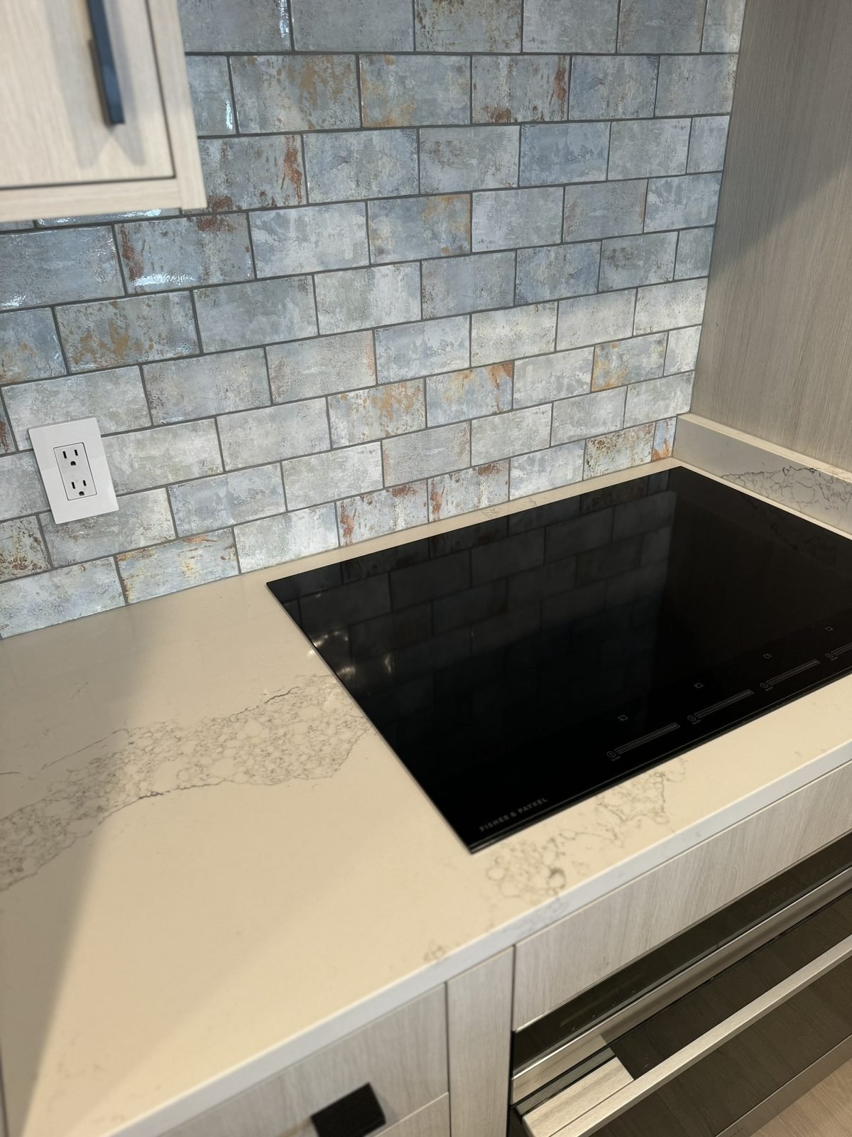 Textured brick-format tile backsplash behind an induction cooktop in a Yaletown kitchen