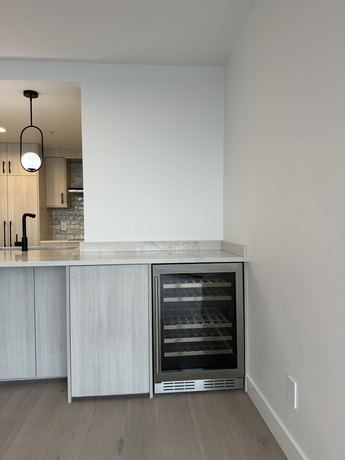 Built-in wine fridge at the end of a quartz island in a Yaletown, Vancouver condo kitchen